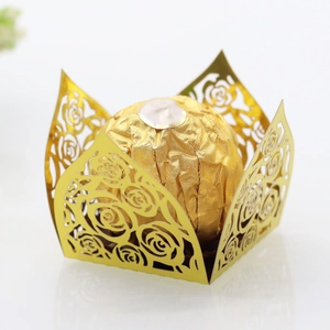 Macro shot of gold laser-cut rose lace paper wrap for wedding party chocolate truffles