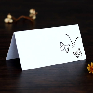 Macro shot of a white laser-cut butterfly place card on a rustic dark wood surface