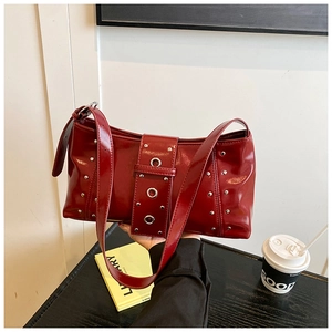 Gros plan d'un sac d'épaule en cuir verni bordeaux avec rivets argentés et œillets métalliques