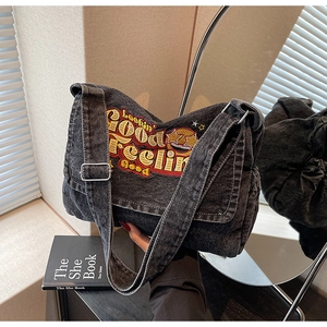 Detail of washed black denim tote bag featuring vintage embroidery and wide strap