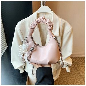 Detailed close-up of light pink pleated hobo bag featuring lace and pearl charms