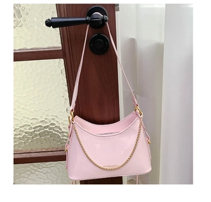 Detail of light pink glossy leather hobo bag with gold chain and branded lettering