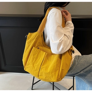 Macro detail of vibrant yellow nylon tote bag featuring crinkled texture and sleek zipper pocket