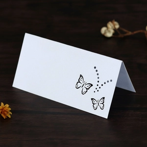 Detail of white hollow butterfly place card with dot patterns on a rustic wood background