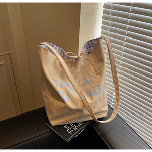Détail du sac cabas en toile beige avec lettrage bleu et doublure à carreaux vichy