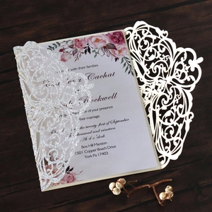 Detail of laser-cut wedding invitation with glitter insert and floral card on wood