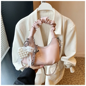 Detailed view of a pink pleated handbag featuring silver chain and pearl heart charm