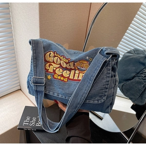 Detail of embroidered star and text on vintage blue denim crossbody tote bag