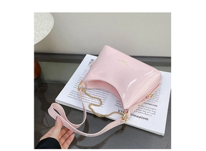 Detail view of pink patent leather shoulder bag with golden chain and branding