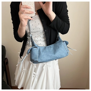 Détail du sac baguette en denim bleu en forme de croissant avec poches latérales à cordon