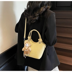 Pale yellow crocodile texture bucket bag with ring handles and plush bear charm detail