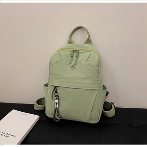 Detail of mint green nylon backpack showing front zip pocket and stylish smiling lanyard