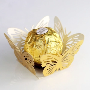 Macro shot of gold laser-cut butterfly lace decorative wrappers for party chocolates