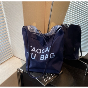 Détail du sac cabas en toile bleue avec imprimé de lettres et doublure à carreaux bleus