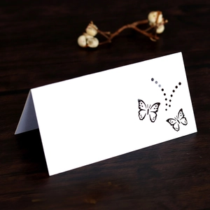 Detailed laser-cut butterfly hollow design on a white kraft paper wedding place card