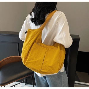 Detail view of large yellow tote bag featuring multiple zipper pockets and fabric texture