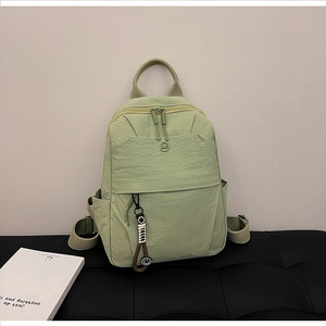 Detail view of mint green waterproof nylon backpack with zipper pulls and smile charm