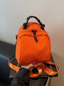 Versatile orange waterproof shell bag with woven handles and nylon shoulder straps for women