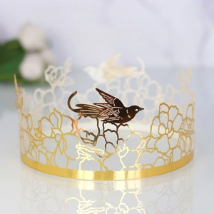 Golden mirror laser-cut cake topper crown with intricate floral vine and bird design