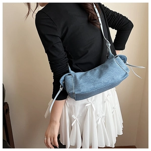 Détail de la texture denim et du nœud décoratif sur le sac à bandoulière bleu ciel