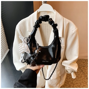 Détail du sac à main noir à poignée plissée avec nœud perlé et finition brillante
