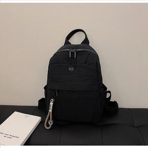 Detail of the water-resistant crinkled nylon fabric and NMC metal logo on black backpack