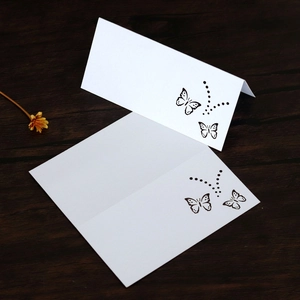 Macro shot of white laser-cut butterfly place cards with hollow patterns on wood background
