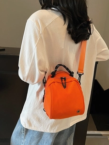 Waterproof orange mini backpack and shoulder bag with woven handle shown on model