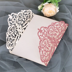 Detail of laser-cut glitter paper wedding invitations with intricate floral patterns