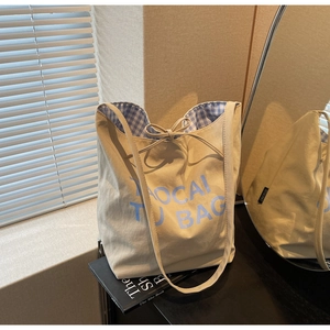 Gros plan d'un sac cabas en toile avec texte bleu et doublure intérieure à carreaux