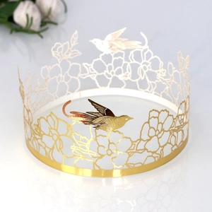 Detailed close-up of golden laser-cut cake border with bird and floral hollow patterns