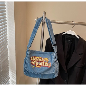 Detail of light blue denim tote featuring 'Lookin Good' colorful embroidery and star patches