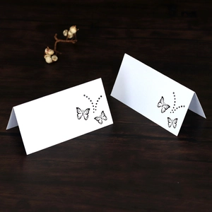 Close-up of white butterfly laser cut place cards on a dark brown wooden table