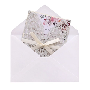 Detail of silver glitter laser cut wedding invitation with ribbon and floral card