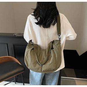 Detail view of large olive green tote bag featuring multiple side pockets and wide strap