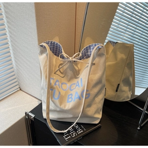 Détail du sac cabas en toile avec lettrage Taocai Tu bleu et doublure à carreaux avec ruban