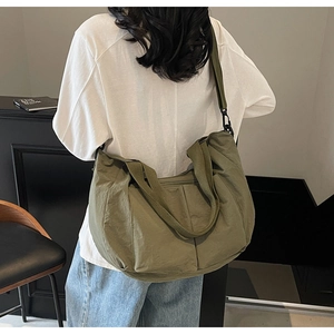 Macro detail of olive green nylon tote bag featuring adjustable strap and side pocket