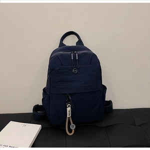 Detail of navy blue nylon backpack with NMC logo and cute smiley face pendant charm