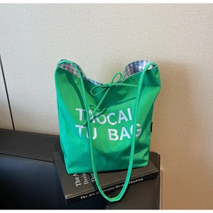 Détail du sac cabas en toile verte montrant la doublure à carreaux et la bandoulière