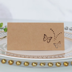 Detailed laser-cut butterfly kraft paper place card on a ceramic dinner plate