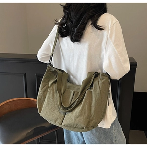Detail view of olive green tote bag showing wrinkled texture and wide crossbody strap