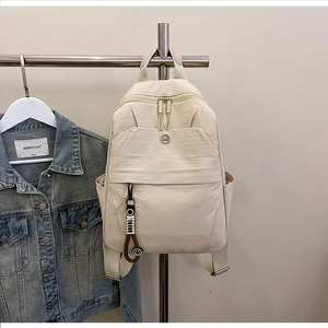 Detail of off-white waterproof nylon backpack with zipper and smiley pendant charm