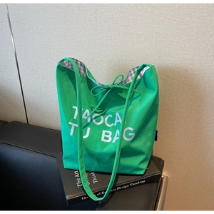 Détail du sac cabas en toile verte avec nœud et doublure à carreaux bleus et blancs