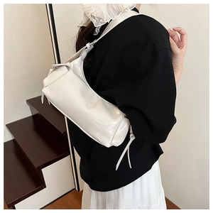 Détail du sac blanc brillant montrant la texture en cuir verni et le cordon latéral