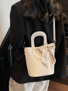 Elegante borsa a secchiello beige grana litchi con foulard di seta sulla modella