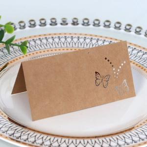 Close-up of laser-cut butterfly kraft paper table card placed on vintage porcelain plate