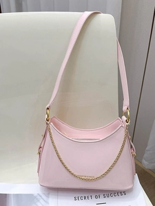 Pink patent leather bucket bag with gold chain strap on a white chair, fashion design