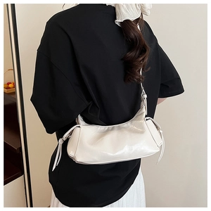 Détail d'un sac à bandoulière demi-lune blanc cassé avec des glands en cuir décoratifs