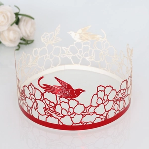 Detailed laser-cut cake border with red metallic bird and floral pattern on a gold base