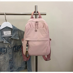 Detailed view of pink nylon backpack with dual zippers and cute smiley pendant